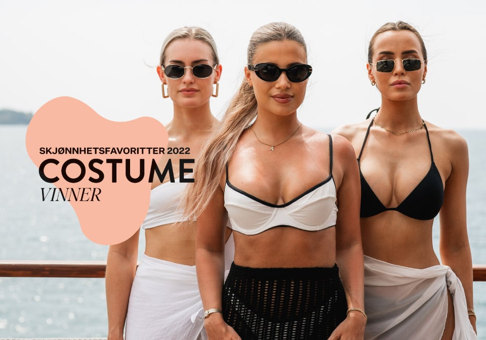 Drei Frauen mit Sonnenbrillen zeigen ihre gebräunte Haut am Strand.