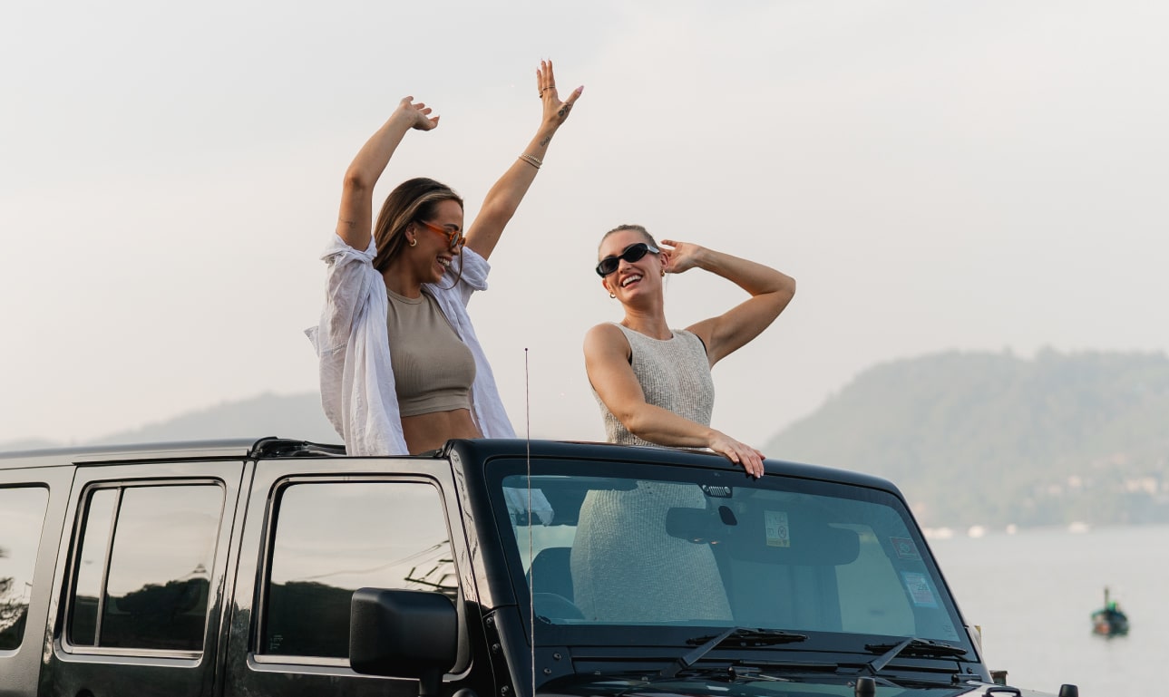 Zwei Frauen genießen in einem Cabriolet das Sonnenlicht